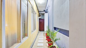 A hallway with a row of potted plants on one side and a door at the end. - Hotel O Btc Guest House Syariah (Malang)