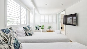 A hotel room with two beds, a TV on the wall, and a small table with a plant.