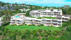A modern multi-story hotel with rooftop pools and a well-maintained lawn.