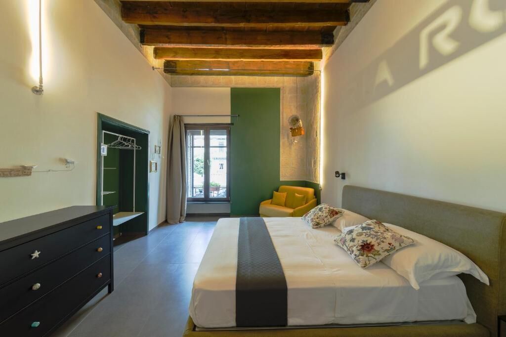 Un dormitorio con una cama, un aparador, una puerta verde y una ventana.
