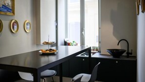 A modern kitchen with a dark countertop, two chairs, a sink, and a window. - Mastropasqua BB (Naples)