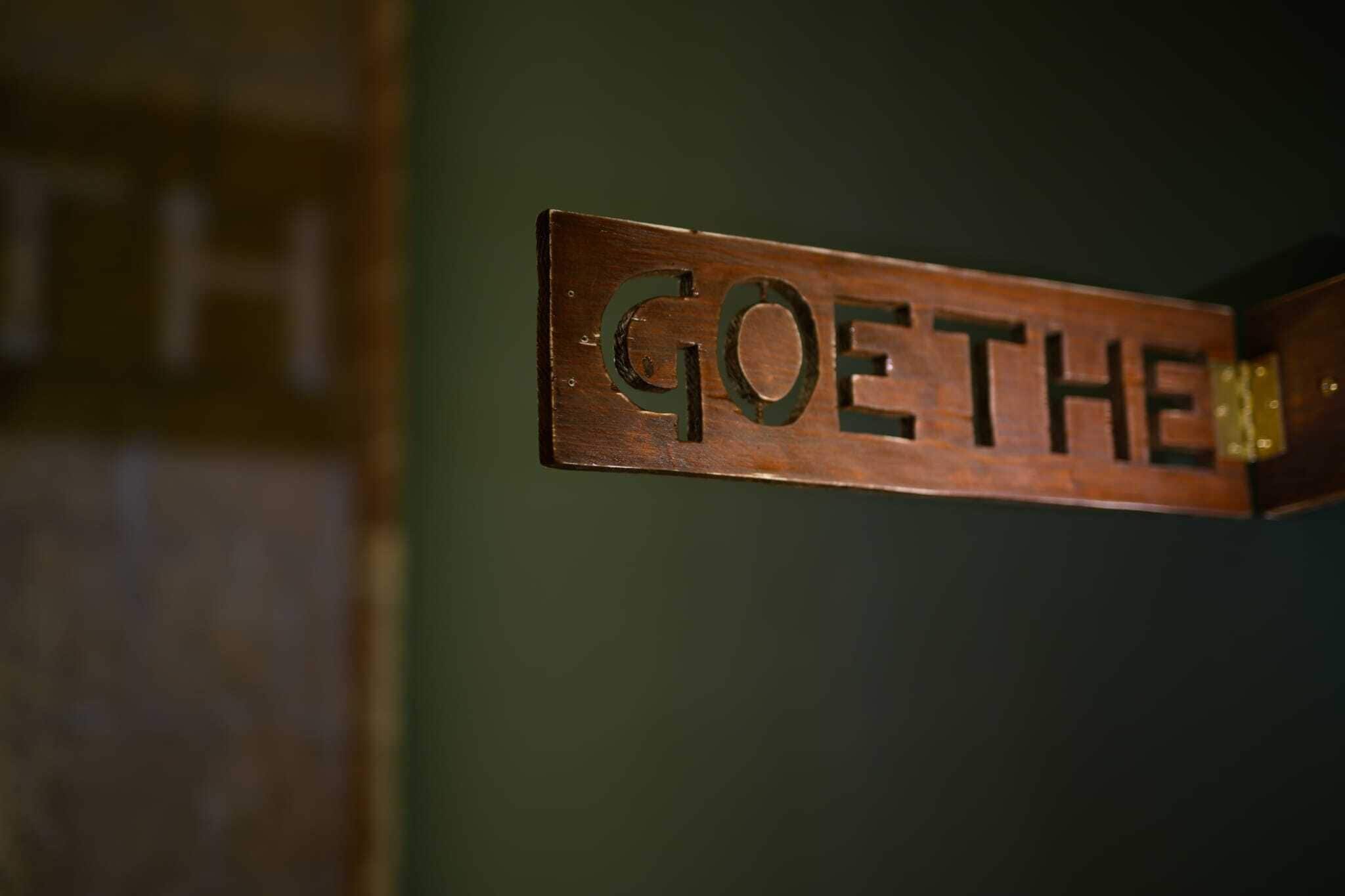 A wooden sign with the name "GOETHE" mounted on a wall.