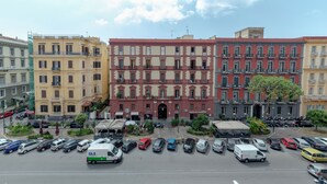 A multi-story building with a central entrance, surrounded by parked cars and a clear sky. - Mastropasqua BB (Naples)