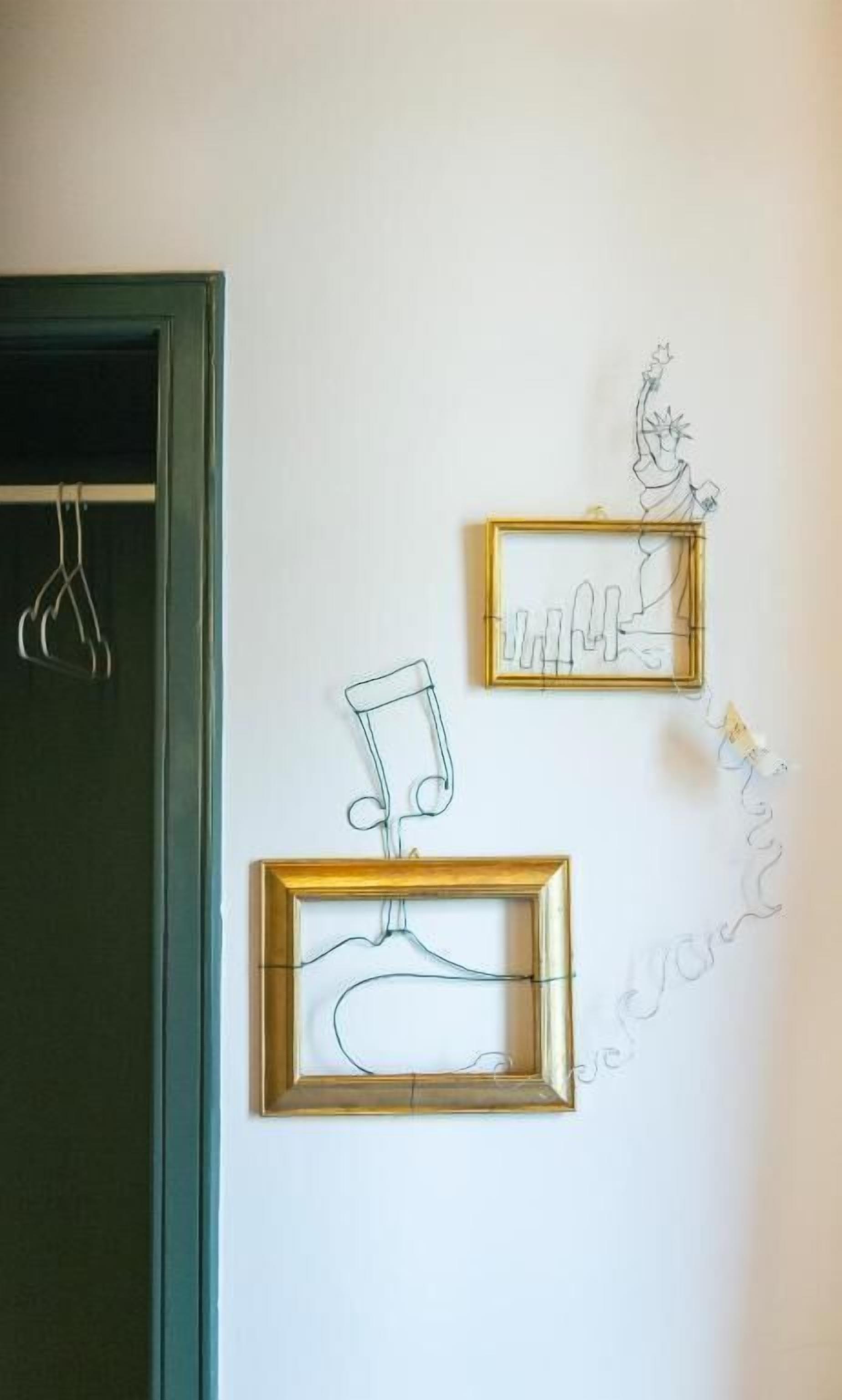 Trois œuvres d’art réalisées à partir de structures filaires sont accrochées à un mur.