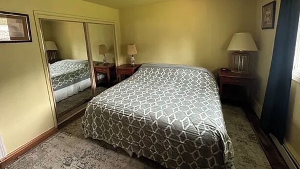 Een hotelkamer met een bed, een spiegel, een nachtkastje en een lamp.