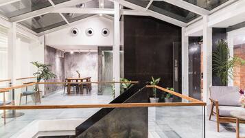 A modern interior with a glass staircase, a dining area, and a seating area with plants.