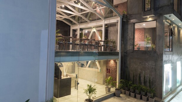 A modern interior with a glass-walled atrium, a mezzanine level, and a brick wall. - 9ine Thamel Hotel (Kathmandu)