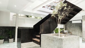A modern interior with a central staircase, a seating area, and a potted plant. - 9ine Thamel Hotel (Kathmandu)