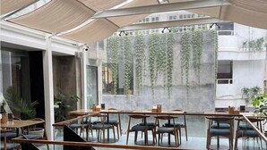 An indoor dining area with tables and chairs, a glass staircase, and hanging plants. - 9ine Thamel Hotel (Kathmandu)