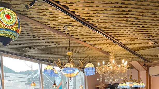 Un groupe de personnes est réuni dans un restaurant doté de grandes fenêtres, d’un plafond en briques et de différents types de luminaires suspendus.