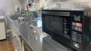 Une cuisine dotée d’un plan de travail en acier inoxydable, d’un four à micro-ondes et d’un évier. On y trouve divers ustensiles de cuisine et une planche à découper en bois sur le plan de travail.