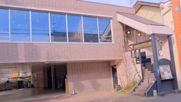 A building with a large window, a covered entrance, and a staircase leading to an upper level.