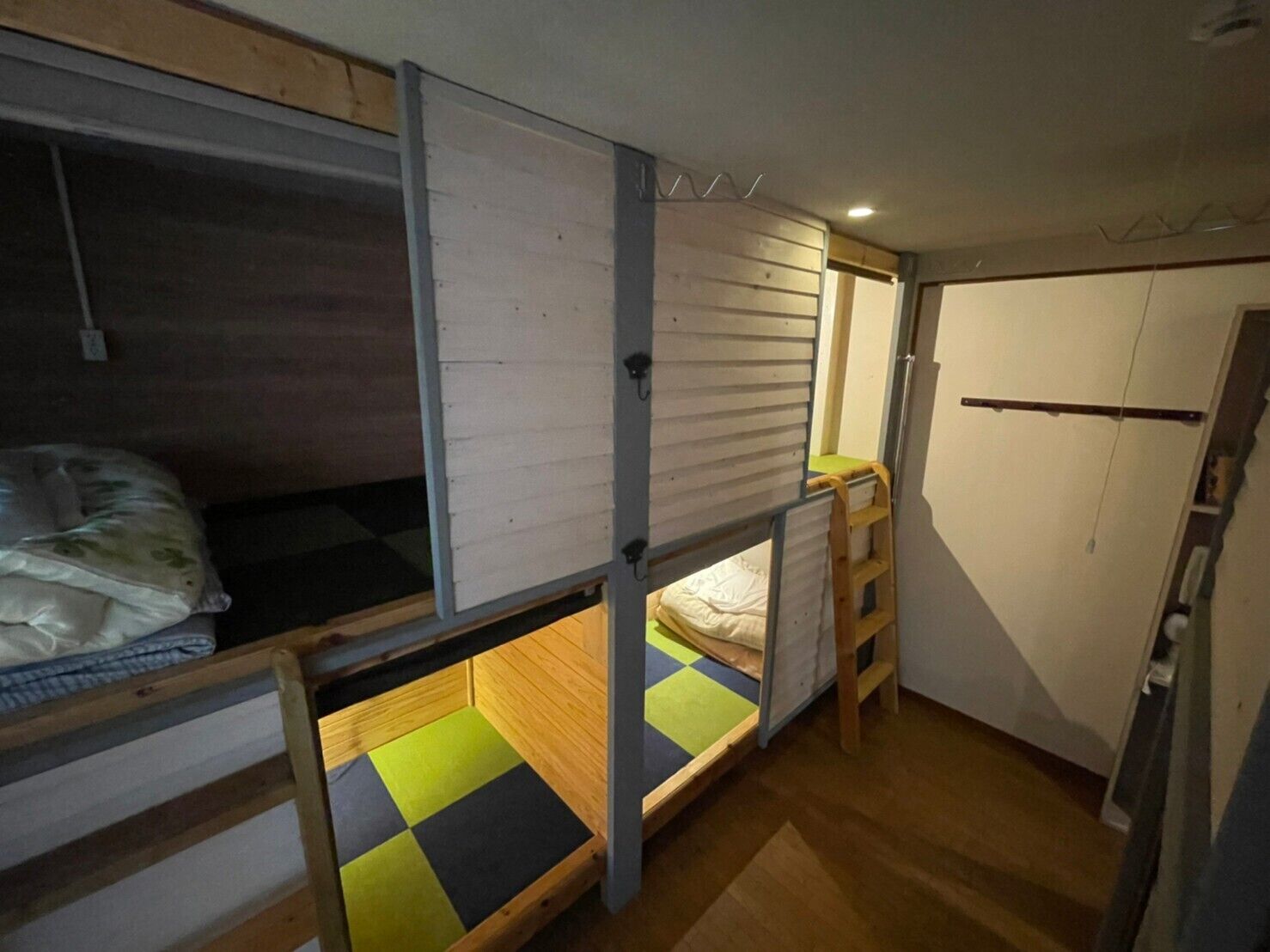 A compact room with bunk beds, a small kitchenette, and a wardrobe.