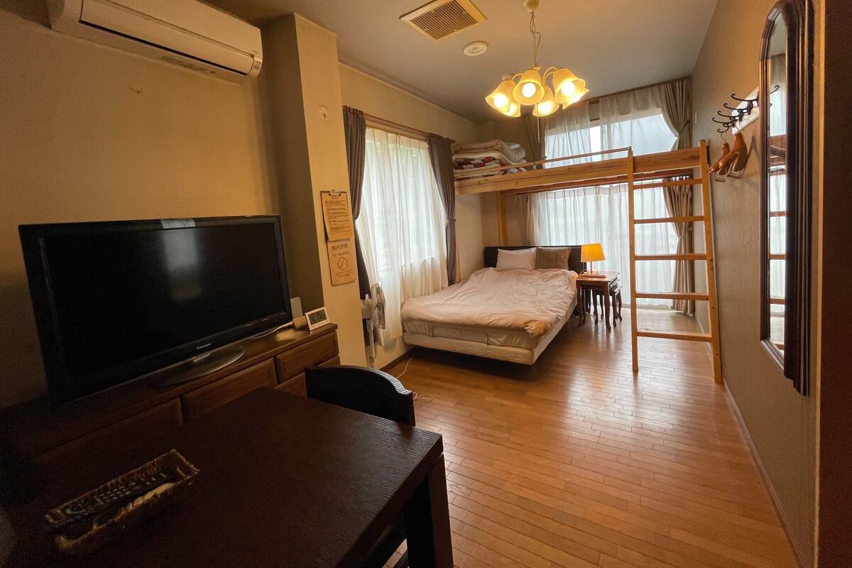 Una habitación de hotel con televisión, literas, muebles de madera y una escalera.
