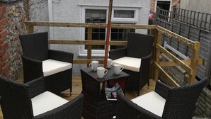 Un patio con muebles de mimbre y un paraguas verde.