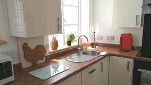 Una cocina con encimera de madera, un lavamanos de acero inoxidable, un microondas y una ventana con vistas al exterior.