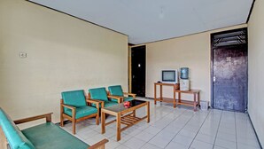 A living room with a sofa, two armchairs, a coffee table, a television, and a water dispenser. - Hotel O Sendang Asri (Wonogiri)
