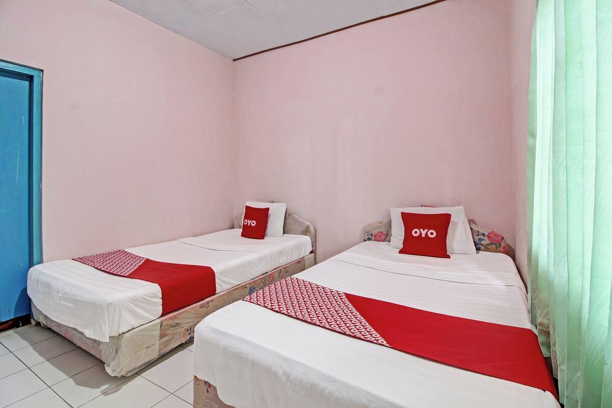 A room with two beds, each with a red and white bedspread and pillows labeled "OYO".