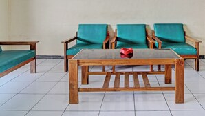 A room with two wooden chairs with green cushions, a wooden table with a red object on it, and a green bed. - Hotel O Sendang Asri (Wonogiri)