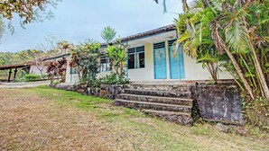 A building with a staircase leading to a door, surrounded by greenery and a clear sky. - Hotel O Sendang Asri (Wonogiri)