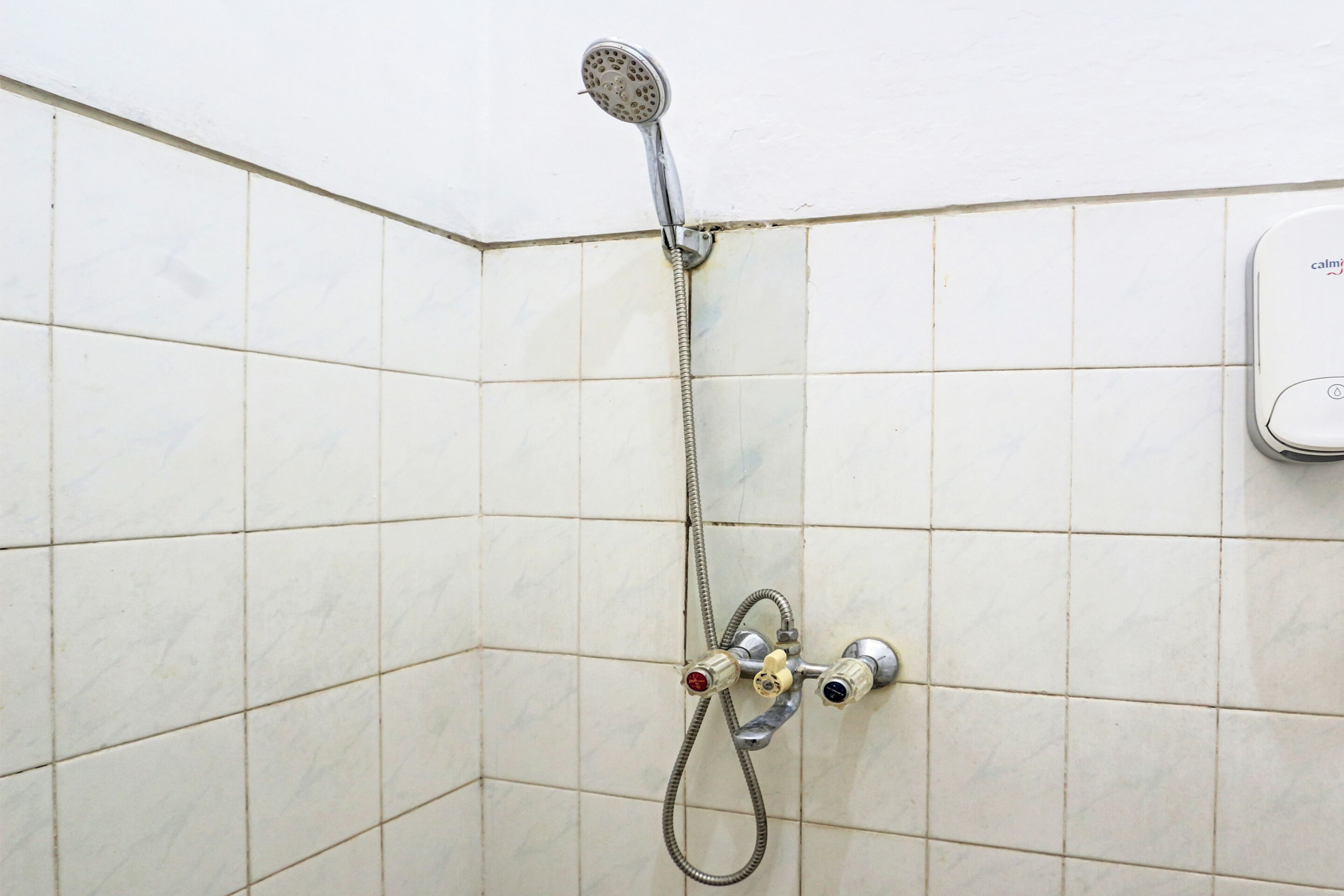 Ducha con cabezal de ducha de mano y panel de control en la pared.