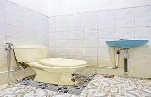 A bathroom with a toilet, a sink, and tiled walls. - Hotel O Sendang Asri (Wonogiri)