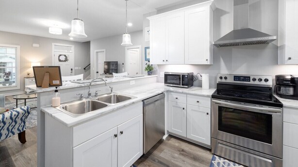 A modern kitchen with white cabinets, stainless steel appliances, and pendant lighting. - Cozy Lake Cottage W/Pool, Hot Tub,Kayaks, SUPs (Winchester)