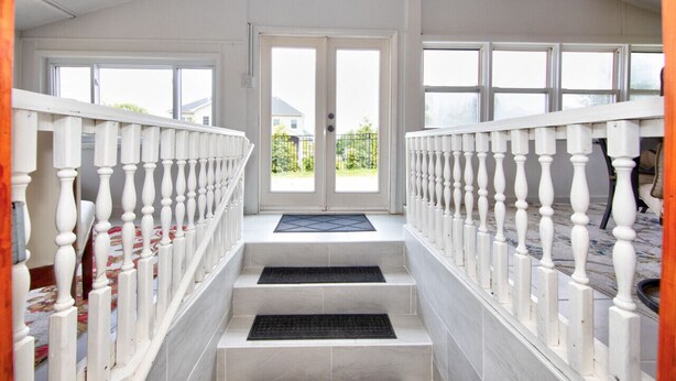 A staircase with white balusters leading to a double door with a view of a house and greenery outside. - Hobbit House one of a kind home (Bel Air)