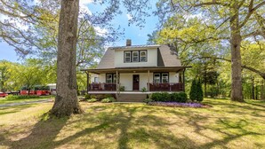 A two-story house with a front porch, surrounded by trees and a well-maintained lawn. - Hobbit House one of a kind home (Bel Air)