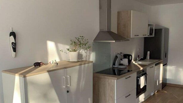 Une cuisine compacte équipée d’un four à micro-ondes, d’une cuisinière et de placards.