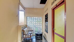 A corridor with a chair, a tire wheel, and a door with a number sign. - SPOT ON 92763 Hotel Melati Sukoasih (Wonogiri)