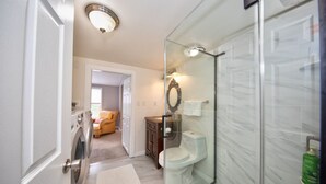 A modern bathroom with a glass shower enclosure, a toilet, and a washing machine. - Watch Deer from a Farm Cottage (Bel Air)