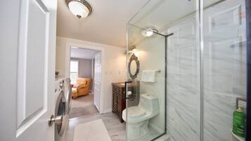 A modern bathroom with a glass shower enclosure, a built-in toilet, and a washing machine.