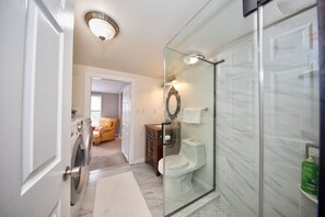 Un baño moderno con cabina de ducha de vidrio, inodoro y lavadora.