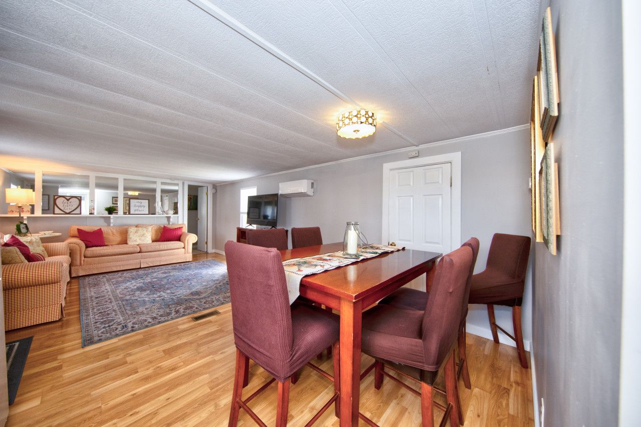 A dining area with a wooden table and chairs, a sofa, and a television in the background.