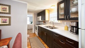 Une cuisine de taille réduite, avec des meubles de couleur sombre, un plan de travail blanc et un four à micro-ondes encastré.