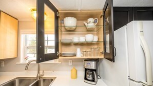 Une cuisine équipée d’un évier à deux bacs, d’une machine à café et d’un réfrigérateur.