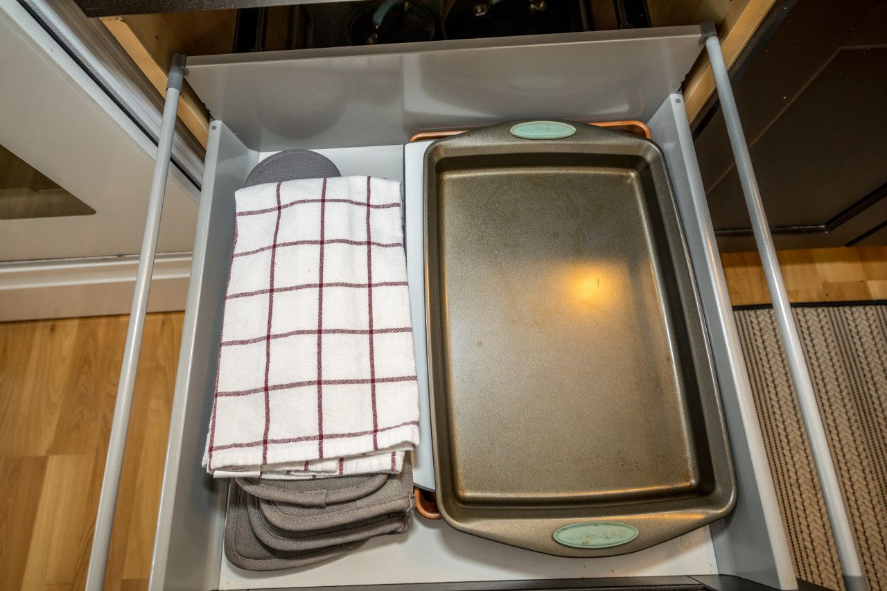 Un tiroir de cuisine contenant une plaque de cuisson et un torchon plié.