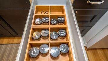 A drawer with multiple compartments containing jars labeled with various spices.