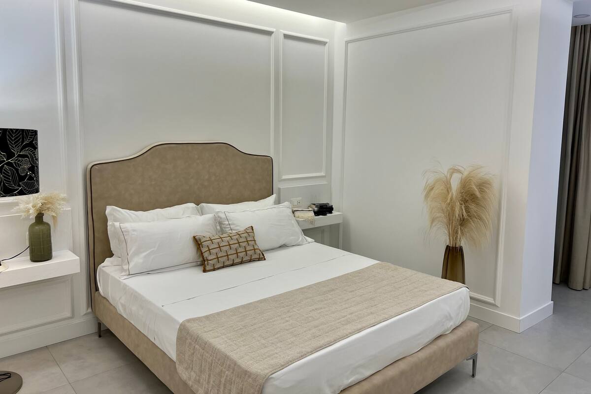 A neatly arranged bedroom with a large bed, bedside tables, and a decorative vase.