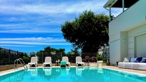 A clear blue pool with white lounge chairs and a white building with a balcony. - Kairos Tropea (Tropea)