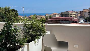 Une terrasse sur le toit, avec deux chaises et une table, d’où l’on peut admirer la vue sur le paysage urbain qui s’étend le long de la côte.