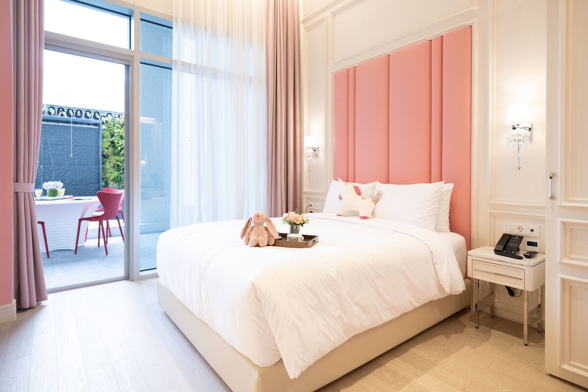 A hotel room with a large bed, a bedside table with a phone, and a window with curtains.