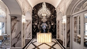 A grand hallway with marble walls, a chandelier, and a marble floor. - The Siena Resort (Seogwipo)