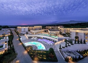 Un hotel moderno con un amplio espacio de piscina, varias construcciones y jardines ajardinados.