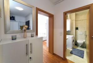 Een moderne badkamer met een wasmachine, toilet en een spiegel boven de wastafel.