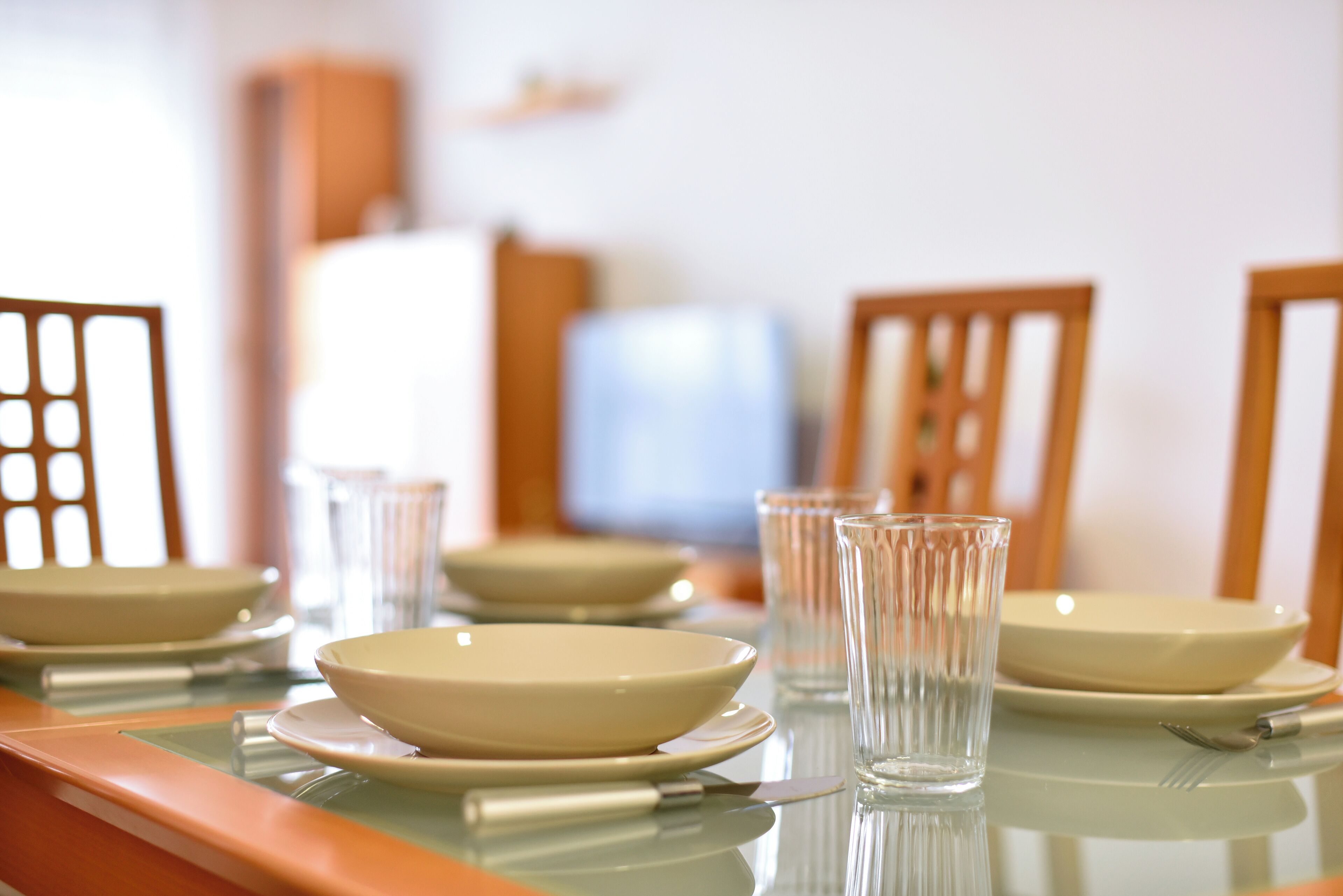 A dining table set with bowls, plates, and glasses, with chairs around it.