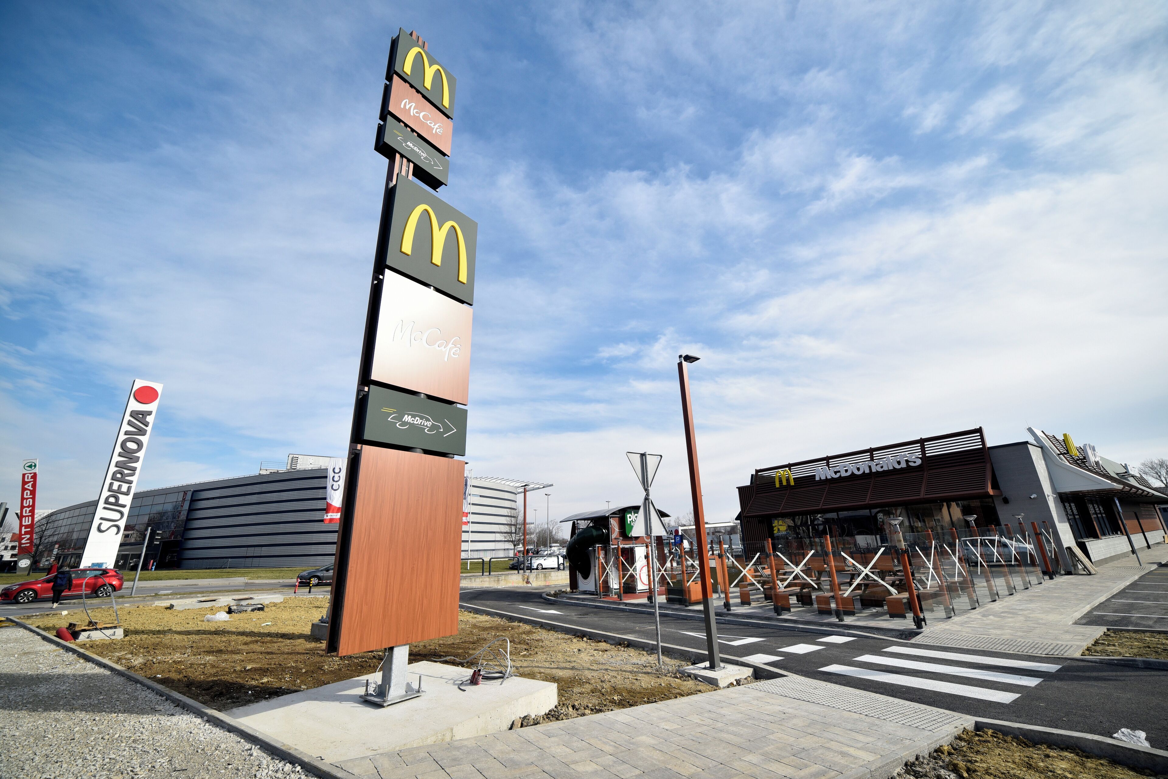 A McDonald's and Supernova sign, a parking area, and a building with a modern design.