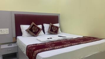 Una cama bien hecha con una colcha blanca y roja, dos almohadas decorativas y una manta roja.