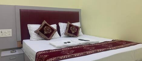 A neatly made bed with a white and red bedspread, two decorative pillows, and a red throw blanket.